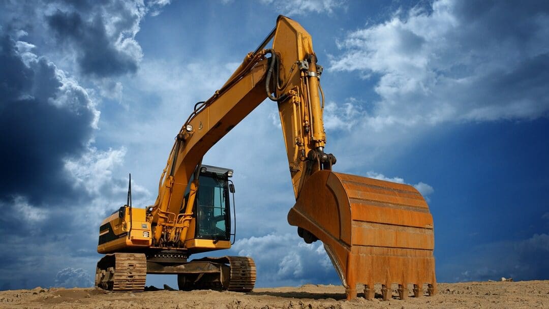 A yellow and black excavator on top of a dirt field.